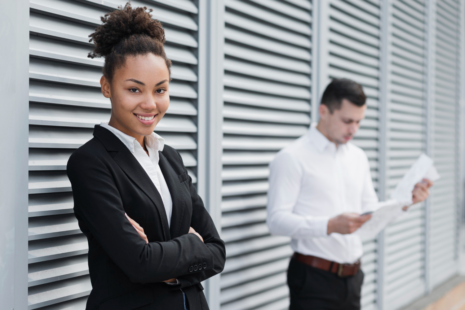 Quais são os direitos dos trabalhadores terceirizados? 1 imagem de mulher de blazer preto, camisa branca e braços cruzados com um homem ao fundo