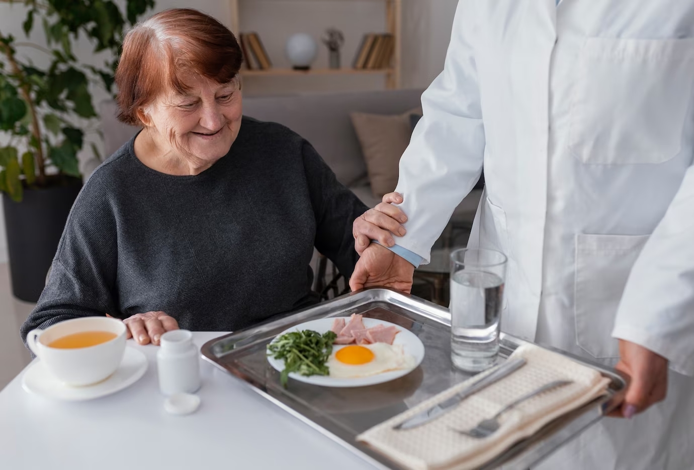 imagem dos braços de uma copeira hospitalar servido café da manhã a uma pessoa idosa