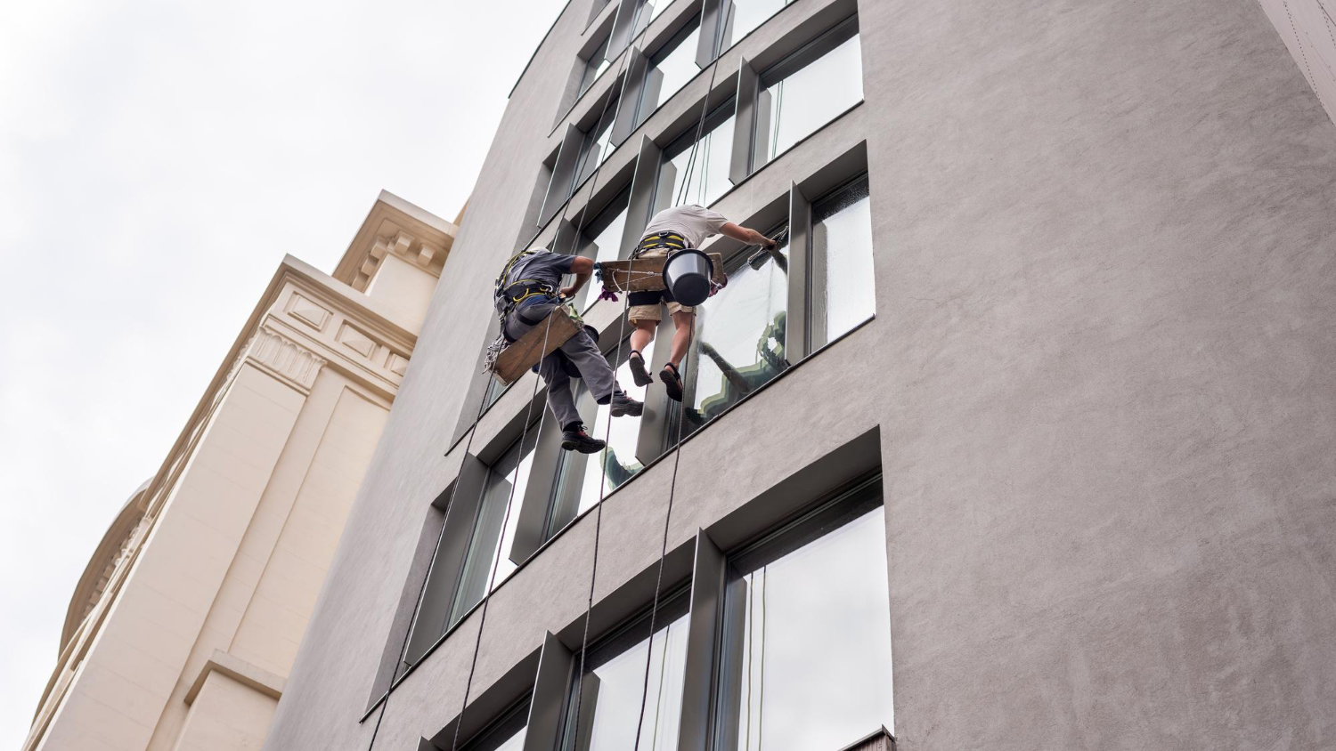 imagem de 2 limpadores de vidro em altura realizando manutenção preventiva
